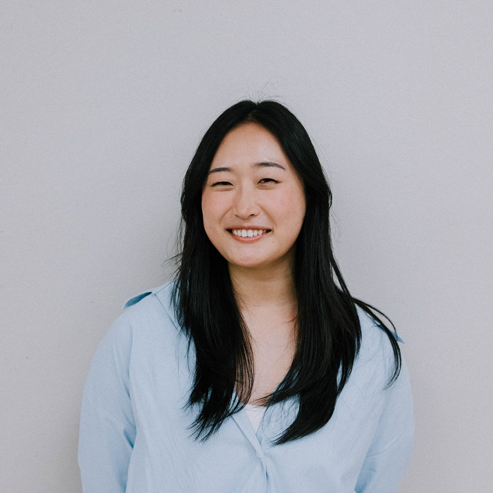 Kate in a light blue shirt against a soft grey backdrop